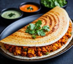 two quesadillas on a plate with sauces and garnishes