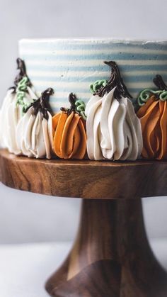 there is a cake decorated with pumpkins on the top and bottom, sitting on a wooden stand