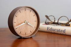 a wooden clock sitting on top of a table next to a book