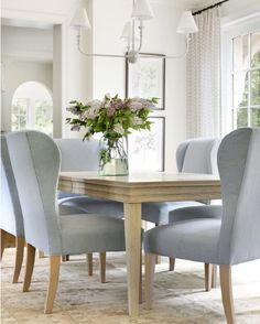 a dining room table with blue chairs and a vase filled with flowers on top of it