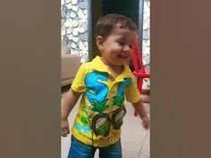 a little boy that is standing up with headphones in his ears and wearing a yellow shirt