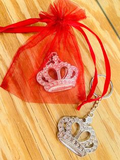 two pieces of jewelry sitting on top of a wooden floor next to a red organ bag