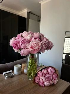 a bouquet of pink peonies in a vase on a table