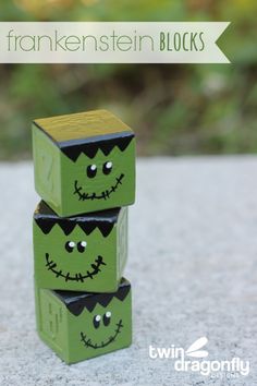 three green cubes with faces painted on them are stacked up in the shape of jack - o - lanterns