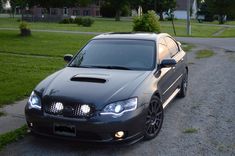 a black car parked on the side of a road next to a grass covered field