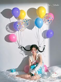 a woman sitting on top of a bed with balloons