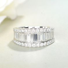 a wedding ring with three baguetts on top and two rows of diamonds around the band