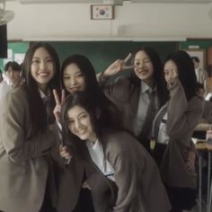 group of young women standing next to each other in front of desks with one woman giving the peace sign