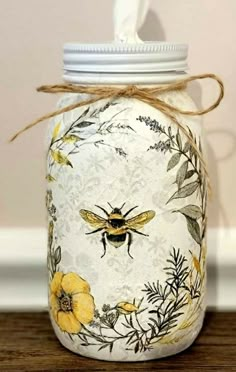 a mason jar with bees and flowers painted on it