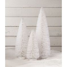 three white plastic trees sitting in the snow