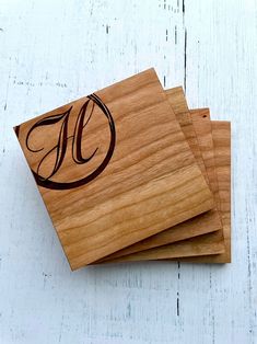 three wooden coasters with monogrammed designs on them sitting on a white table