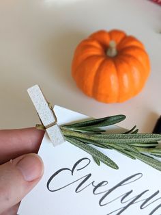 a person holding up a piece of paper with the word grateful written on it and an orange pumpkin in the background