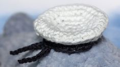 a crocheted white and black object sitting on top of a gray rock in the sky