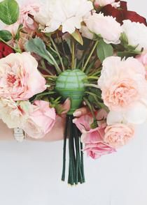 a bouquet of pink and white flowers in someone's arm with green vase on it