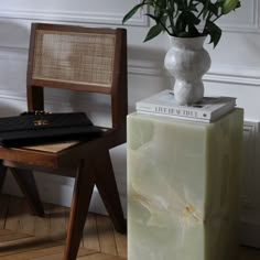 a white vase sitting on top of a green block next to a chair and table