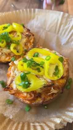 two pieces of food sitting on top of a piece of wax paper covered in green onions