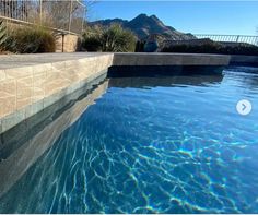 an empty swimming pool with blue water and mountains in the backgroung area