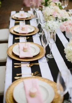 black and white striped table cloth with pink napkins, gold chargers and place settings