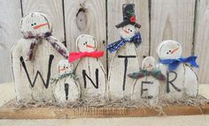 a group of snowmen standing in front of a wooden fence with the word winter written on it