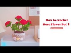 a potted plant with red roses in it on a white table next to a lamp