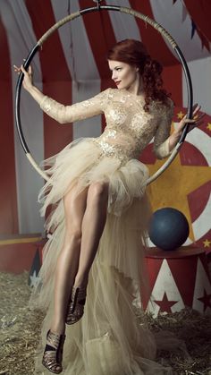 a woman in a dress is sitting on a hoop with an american flag backdrop behind her