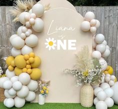 a table topped with balloons and flowers next to a sign that says lanaa is one