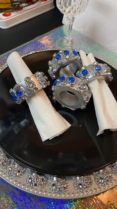 a black plate topped with napkins and two silver rings on top of each other