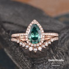 a green and white diamond ring on top of a rock