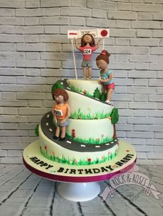 a three tiered cake decorated with children on the top and street signs above it