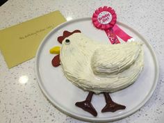 a cake shaped like a chicken on a plate with a pink ribbon around its neck