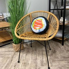 a sushi pillow sitting on top of a chair next to a potted plant