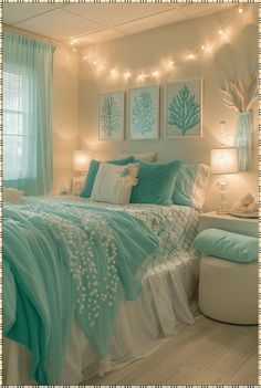 a bedroom decorated in aqua and white with lights strung above the bed, along with pictures on the wall