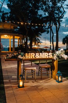 the reception table is set up outside at night with lights strung over it and flowers on top