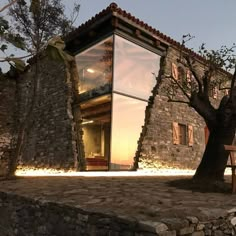 a house made out of rocks with a tree next to it