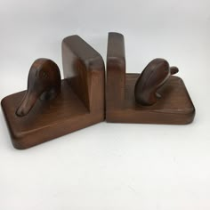 two wooden birds are sitting on top of each other in the shape of bookends