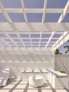 an outdoor living area with white furniture and pergolated roof