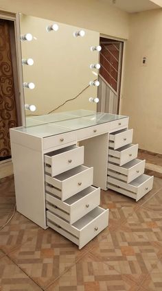 a white vanity with drawers and lights on the top shelf in front of a mirror