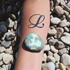 a person's arm with a rock and the letter l on it