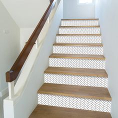 a set of stairs with wooden handrails and white chevron tiles on them