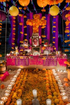 a decorated table with candles and pictures on the wall, surrounded by flowers and lanterns