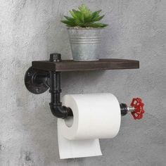 a toilet paper holder with a potted plant on the top and two rolls of toilet paper attached to it