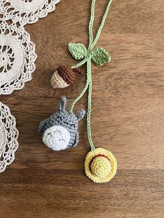 three crocheted ornaments are hanging from a string on a wooden table with doily