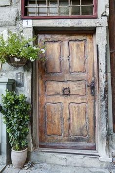 an old wooden door with two planters next to it