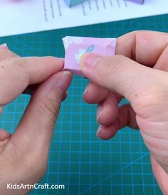 two hands are holding an origami piece