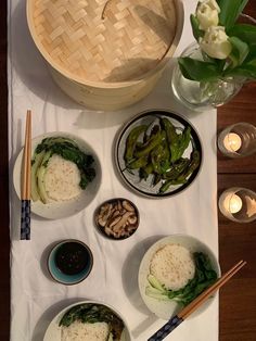 a table topped with bowls filled with food and chopsticks next to a basket