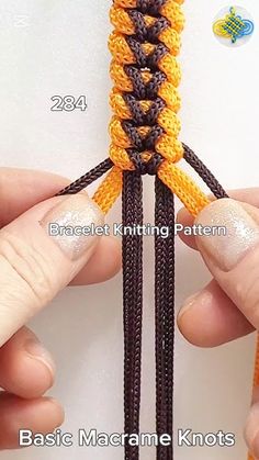 two hands are holding an orange and black crochet piece with the ends facing each other