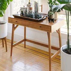 a wooden table topped with plants next to a window