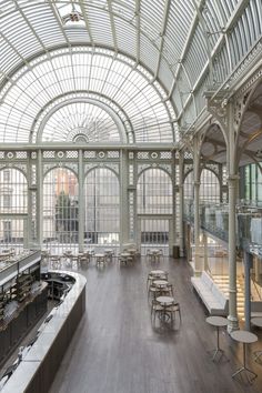 the inside of a building with many tables and benches in front of windows on both sides