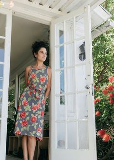 a woman standing in the doorway of a house with flowers on it's dress