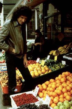 a man standing in front of a fruit stand